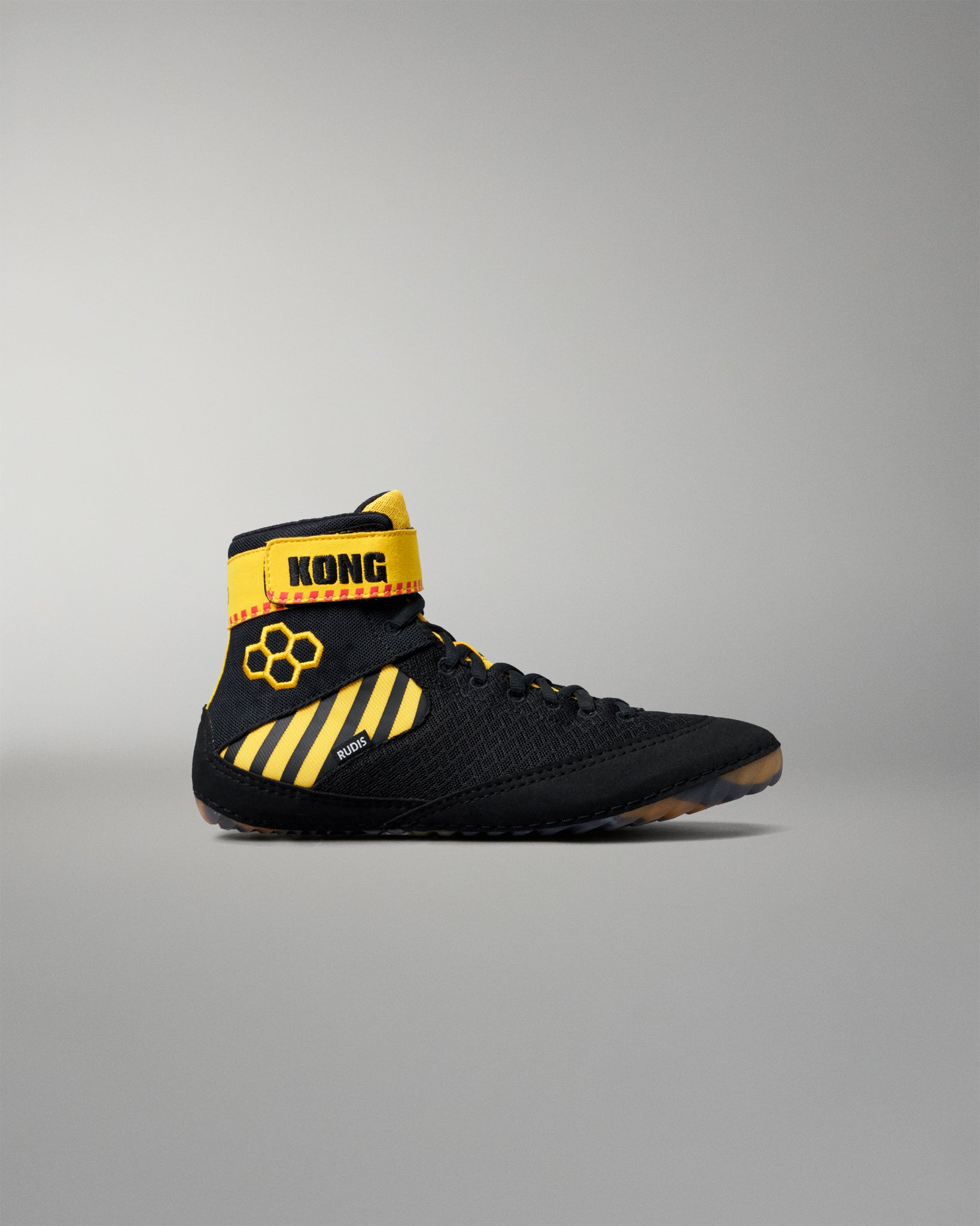 A black high-top wrestling shoe with bright yellow accents, including a yellow ankle strap labeled 'KONG' and yellow diagonal stripes on the side, shown against a neutral gray background.