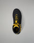A black wrestling shoe with bright yellow accents, including the laces, collar lining, and side stripes, shown from a top-down view on a neutral gray background.