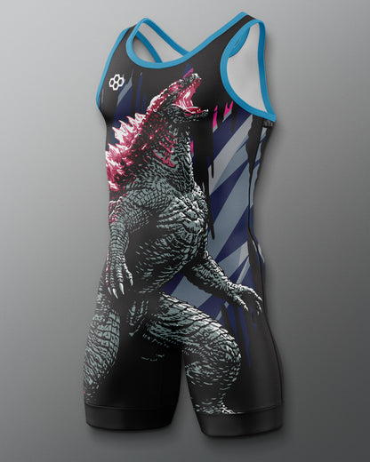 A sleeveless wrestling singlet with a large Godzilla graphic print, featuring a black body with blue trim, white diagonal stripes on the sides, and pink accents on the creature's back, shown against a gray gradient background.