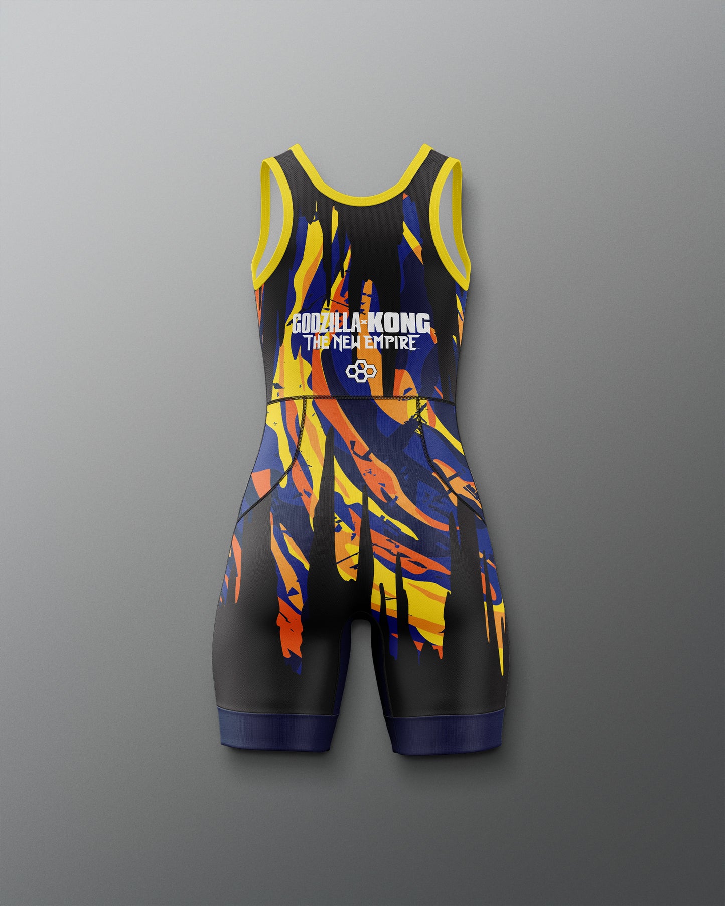 A sleeveless athletic one-piece wrestling singlet with a black base and a bold abstract flame-like pattern in yellow, orange, and blue. The jumpsuit features 'Godzilla x kong THE NEW EMPIRE' printed in white on the chest, set against a neutral gray background.