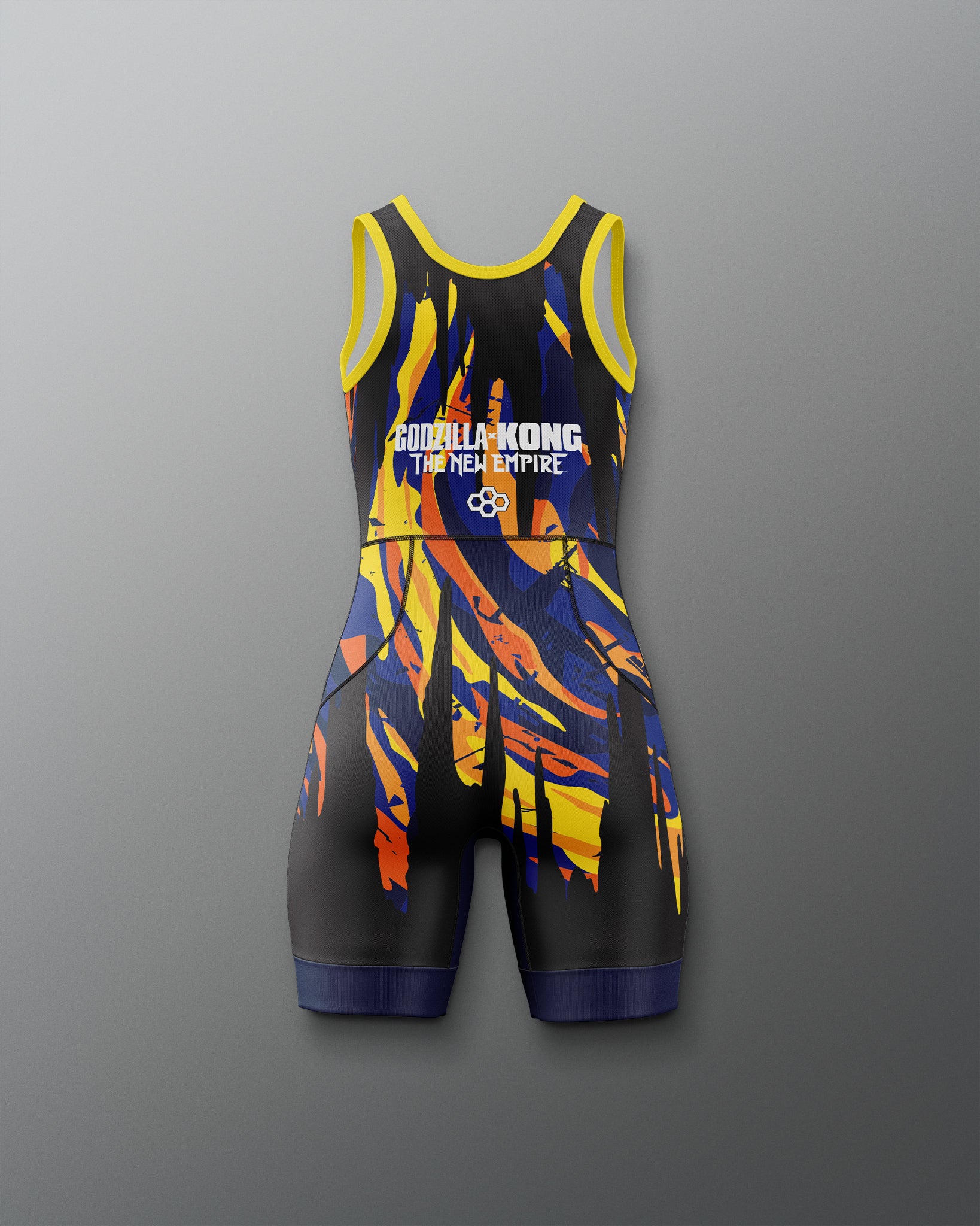 A sleeveless athletic one-piece wrestling singlet with a black base and a bold abstract flame-like pattern in yellow, orange, and blue. The jumpsuit features 'Godzilla x kong THE NEW EMPIRE' printed in white on the chest, set against a neutral gray background.