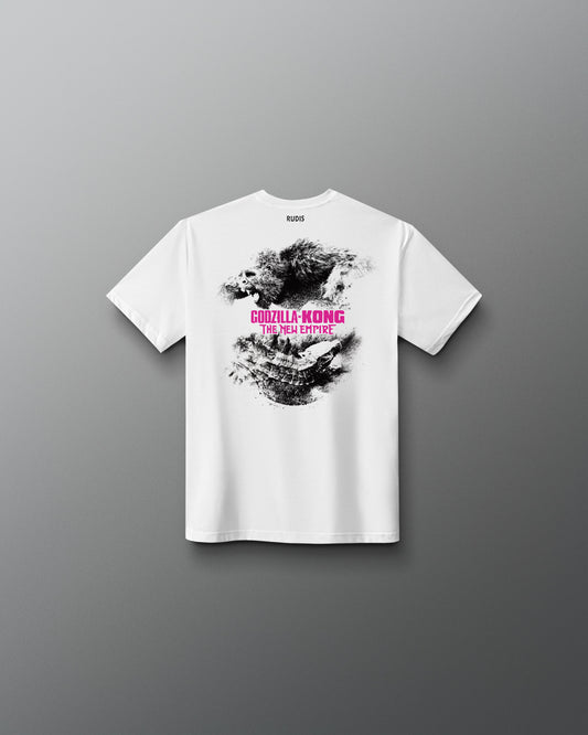A white short-sleeve t-shirt shown from the back, featuring a black and gray splattered graphic with pink text reading 'Godzilla KONG' and smaller text below, displayed against a dark gray gradient background.