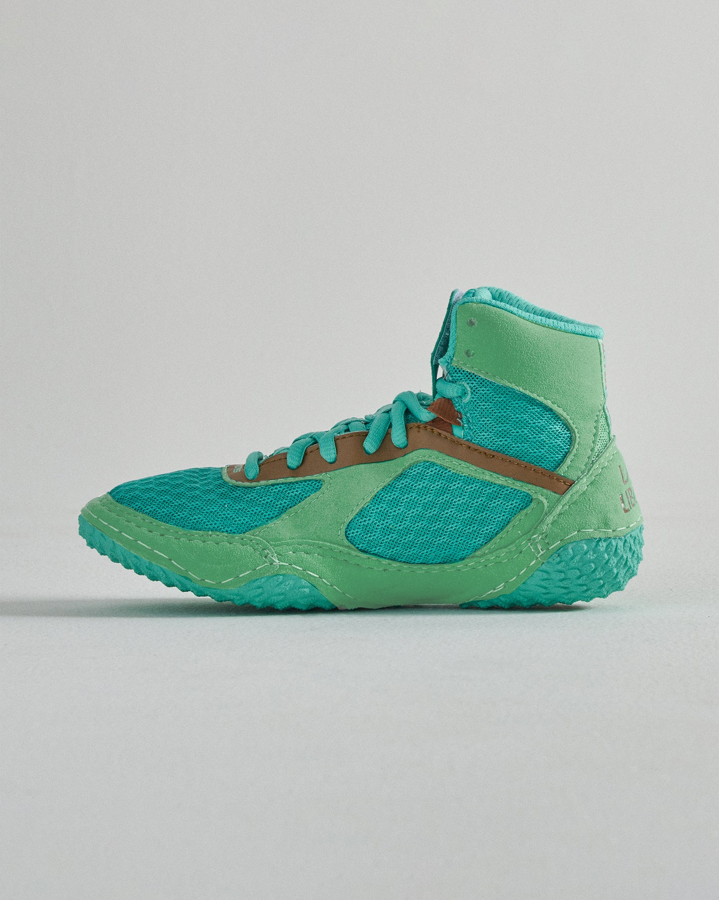 A vibrant turquoise athletic shoe designed for performance featuring a breathable mesh upper a supportive high-top design and a textured sole for grip