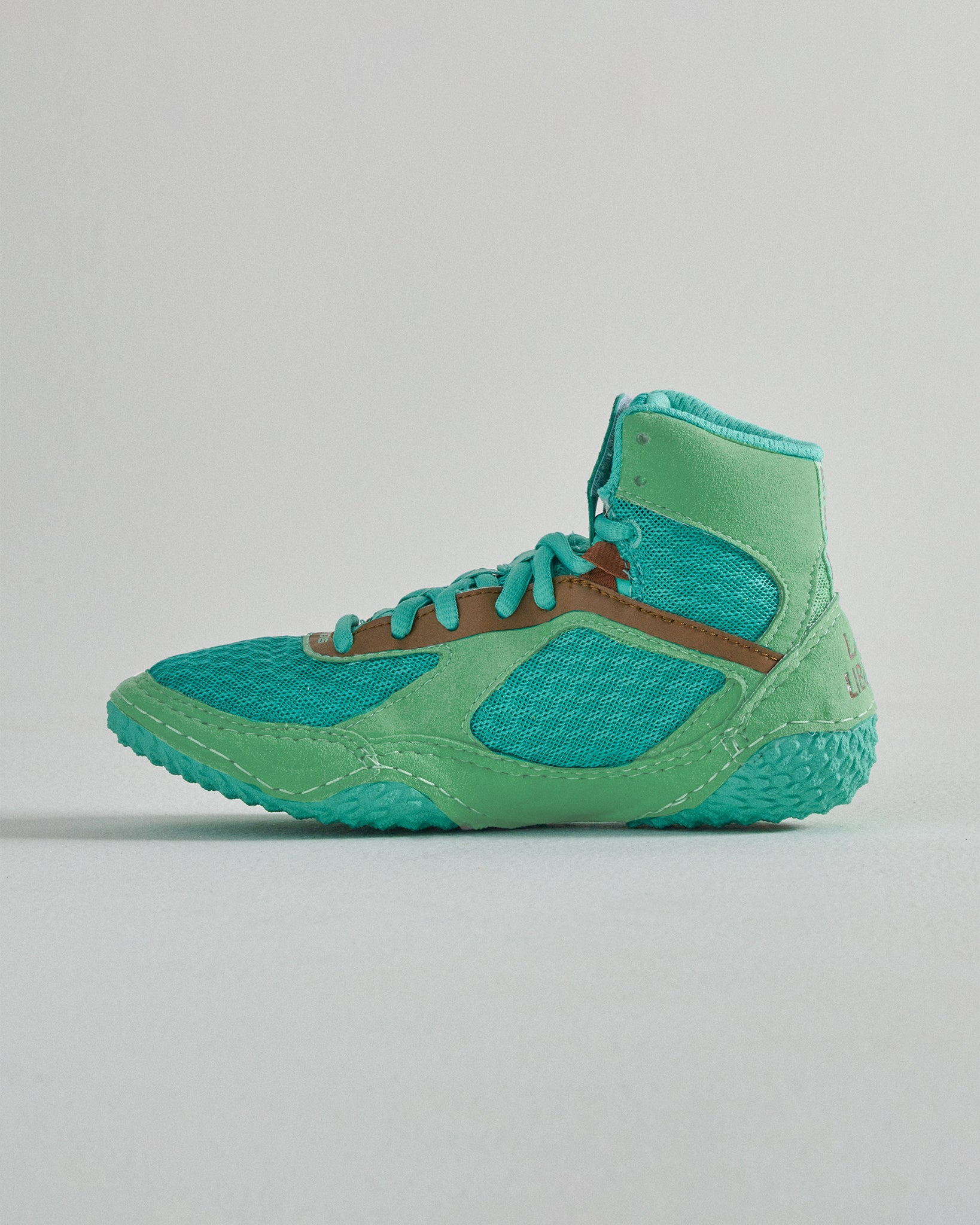 A vibrant turquoise athletic shoe designed for performance featuring a breathable mesh upper a supportive high-top design and a textured sole for grip