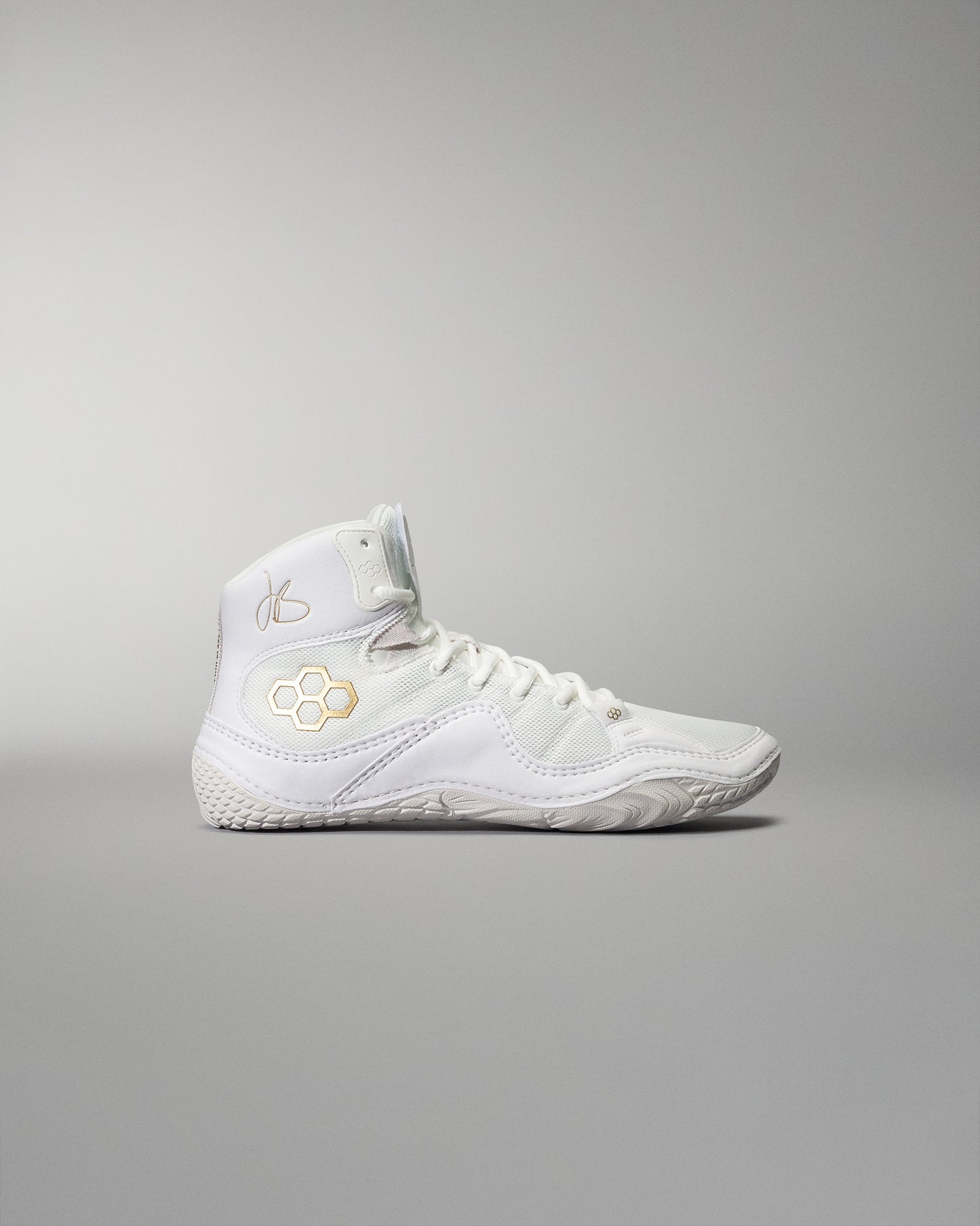 High-top white athletic shoe with intricate detailing, a padded collar for support, and a textured sole for grip, accentuated by gold elements against a soft gray background.
