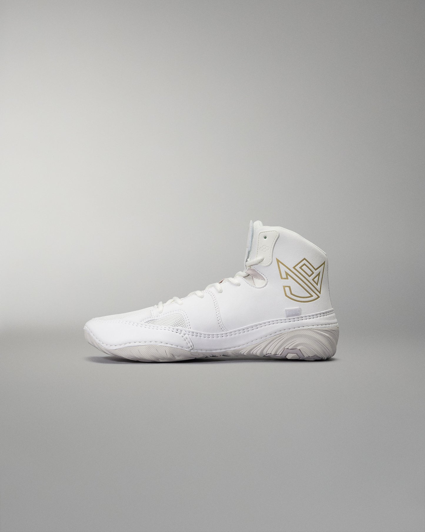 White high-top athletic shoe with smooth design, gold logo detail, and textured sole for grip against a soft gray background.