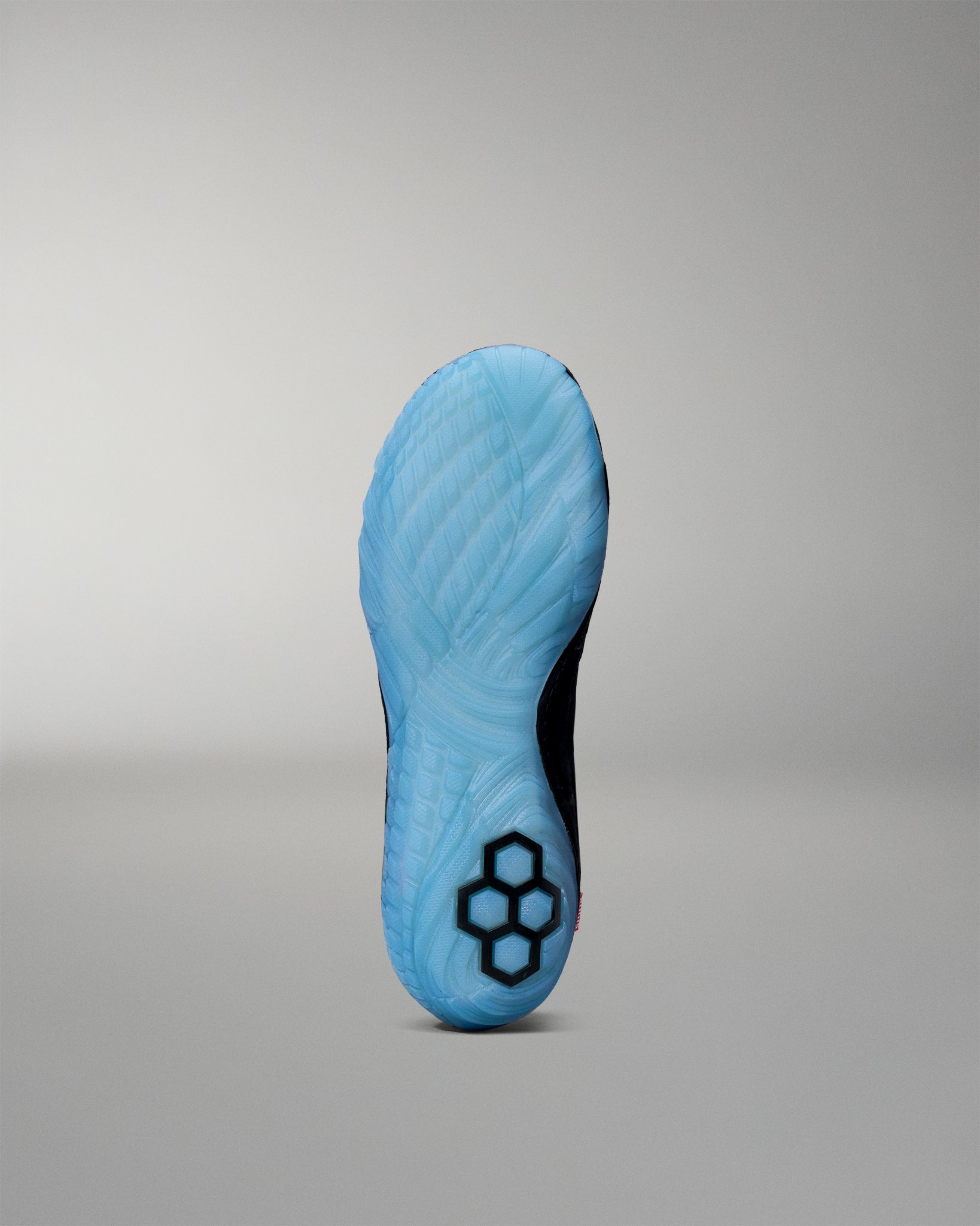 Blue wrestling shoe sole with a honeycomb pattern on a gray background