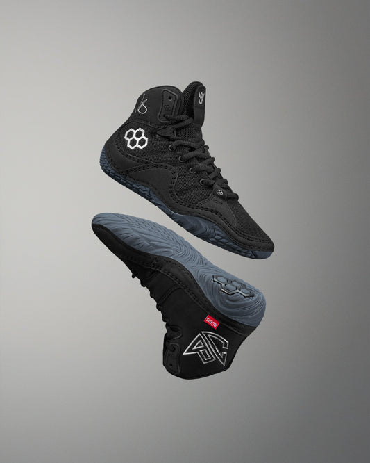 Black high-top wrestling shoe with brand logo on a gray background