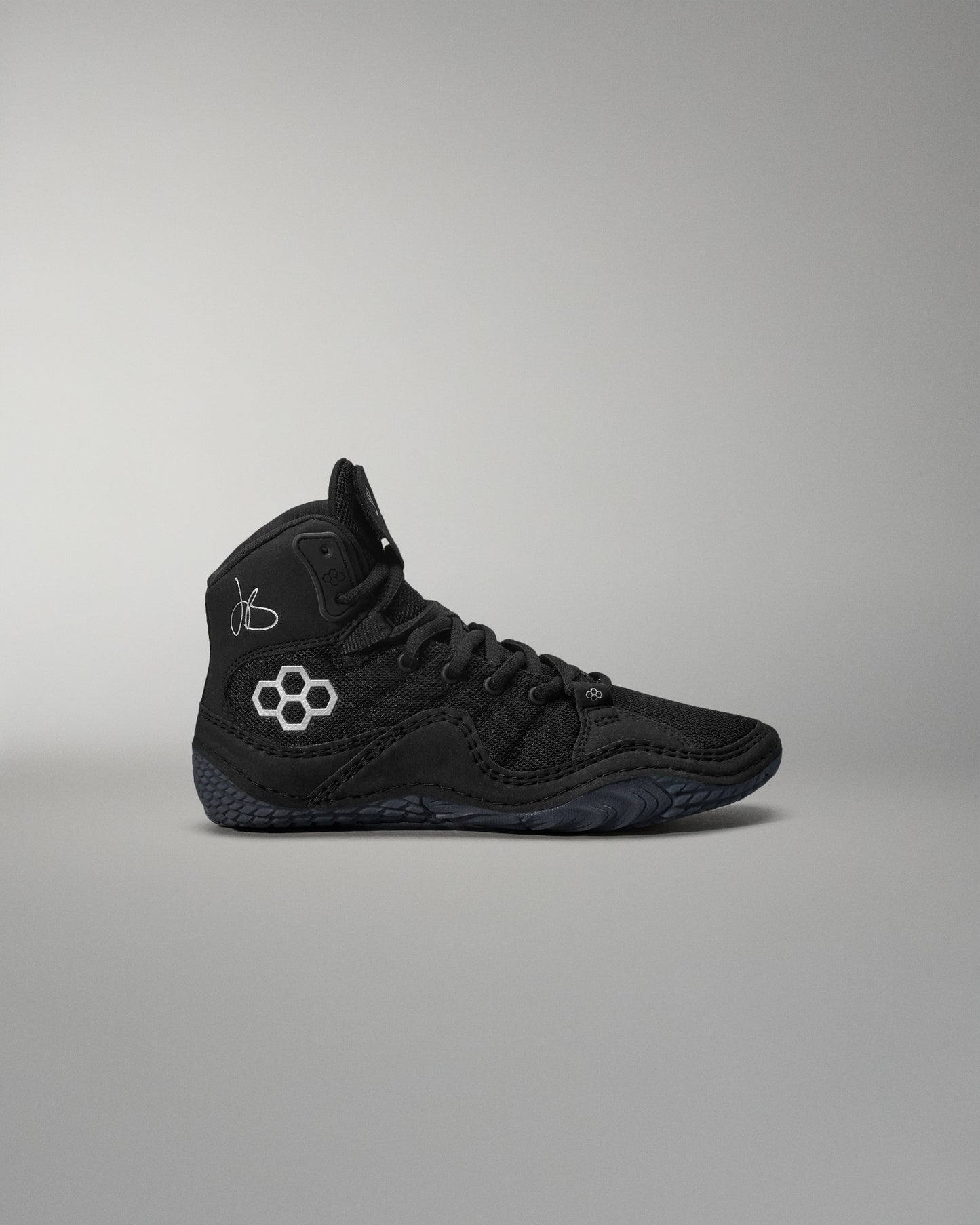 Black high-top wrestling shoe with a logo on a gray background