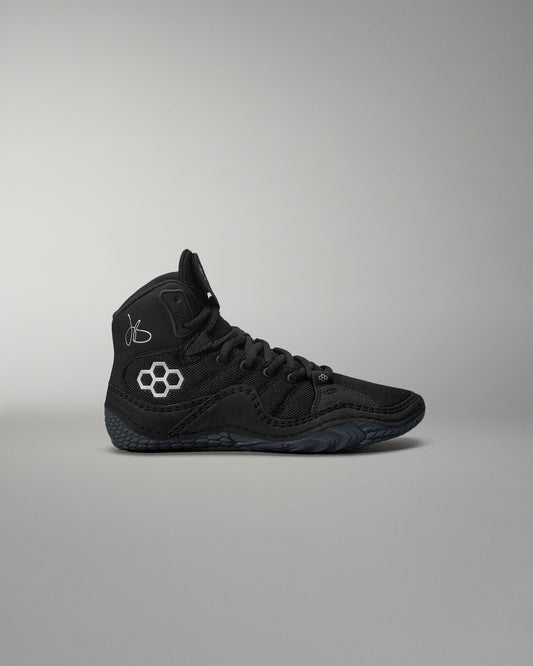 Black high-top wrestling shoe with a logo on a gray background