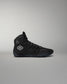 Black high-top wrestling shoe with a logo on a gray background