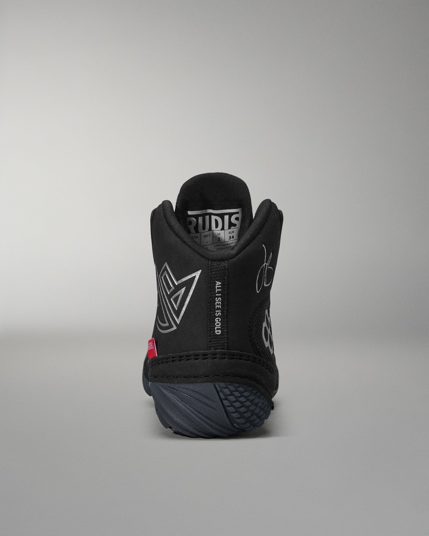 Black wrestling shoe with visible branding on a gray background