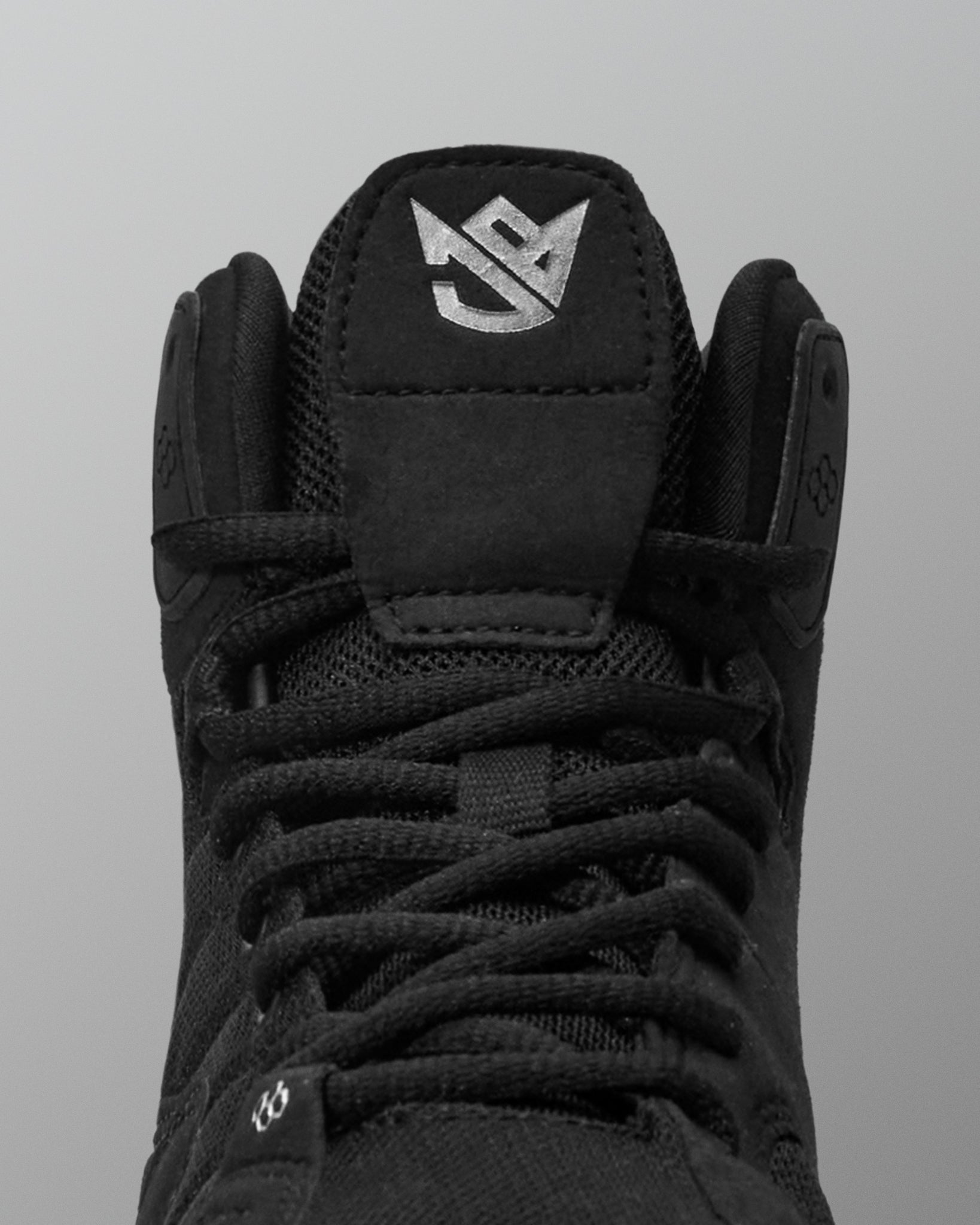 Black wrestling shoe with a brand logo on a gray background