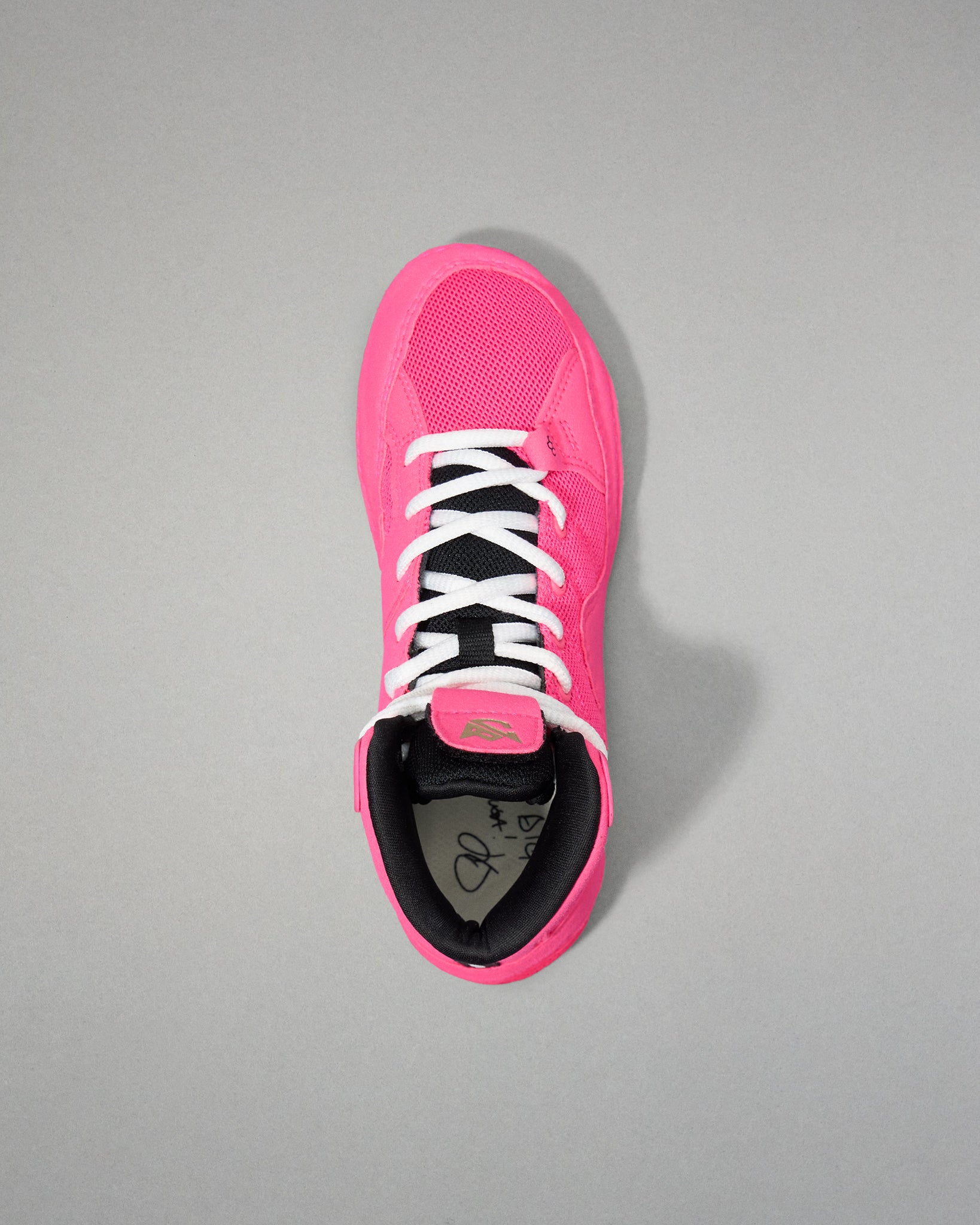 Pink wrestling shoe with black sole on a gray background