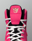 Close-up of a pink and black wrestling shoe with white laces on a gray background