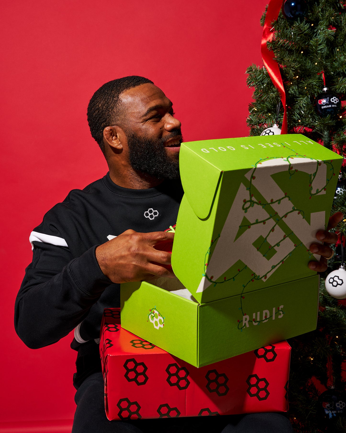 Man opening a green shoe box with a Christmas tree in the background