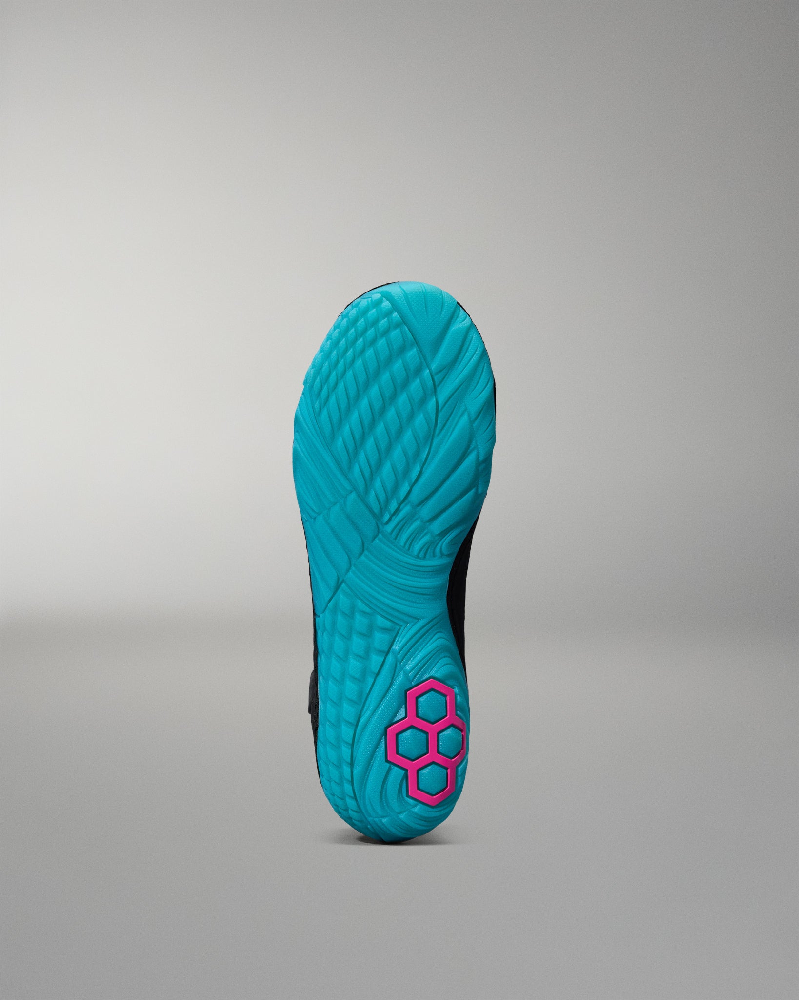 Turquoise sole of a wrestling shoe with a pink hexagonal logo on a gray background