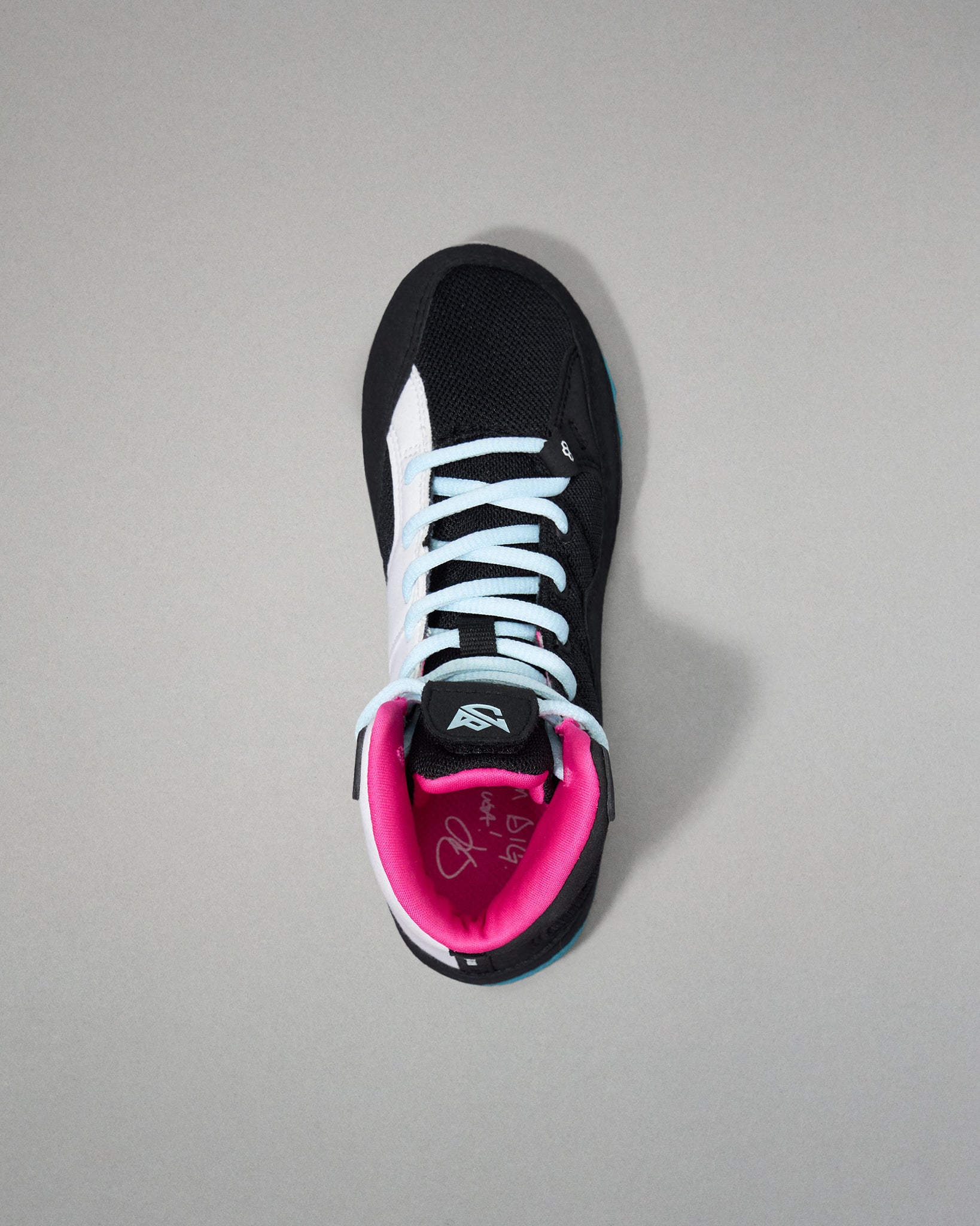 Black wrestling shoe with pink lining on a gray background