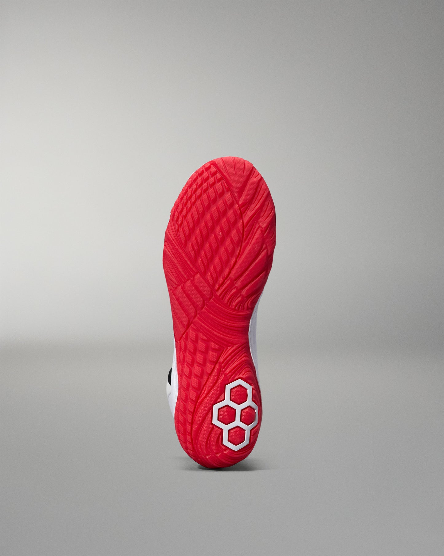 Red wrestling shoe sole with a textured pattern on a gray background