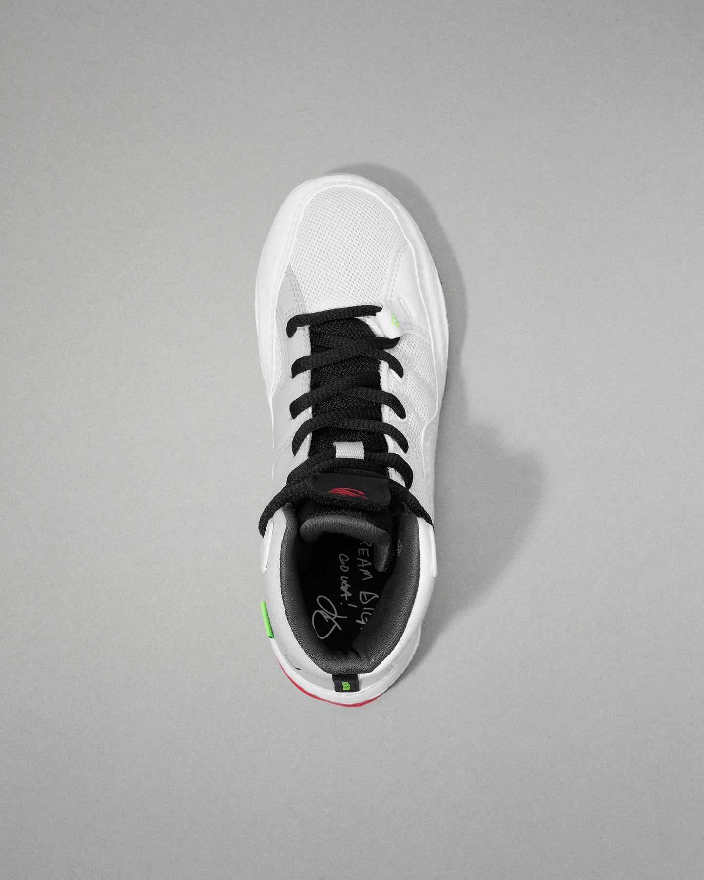 White wrestling shoe with black laces on a gray background