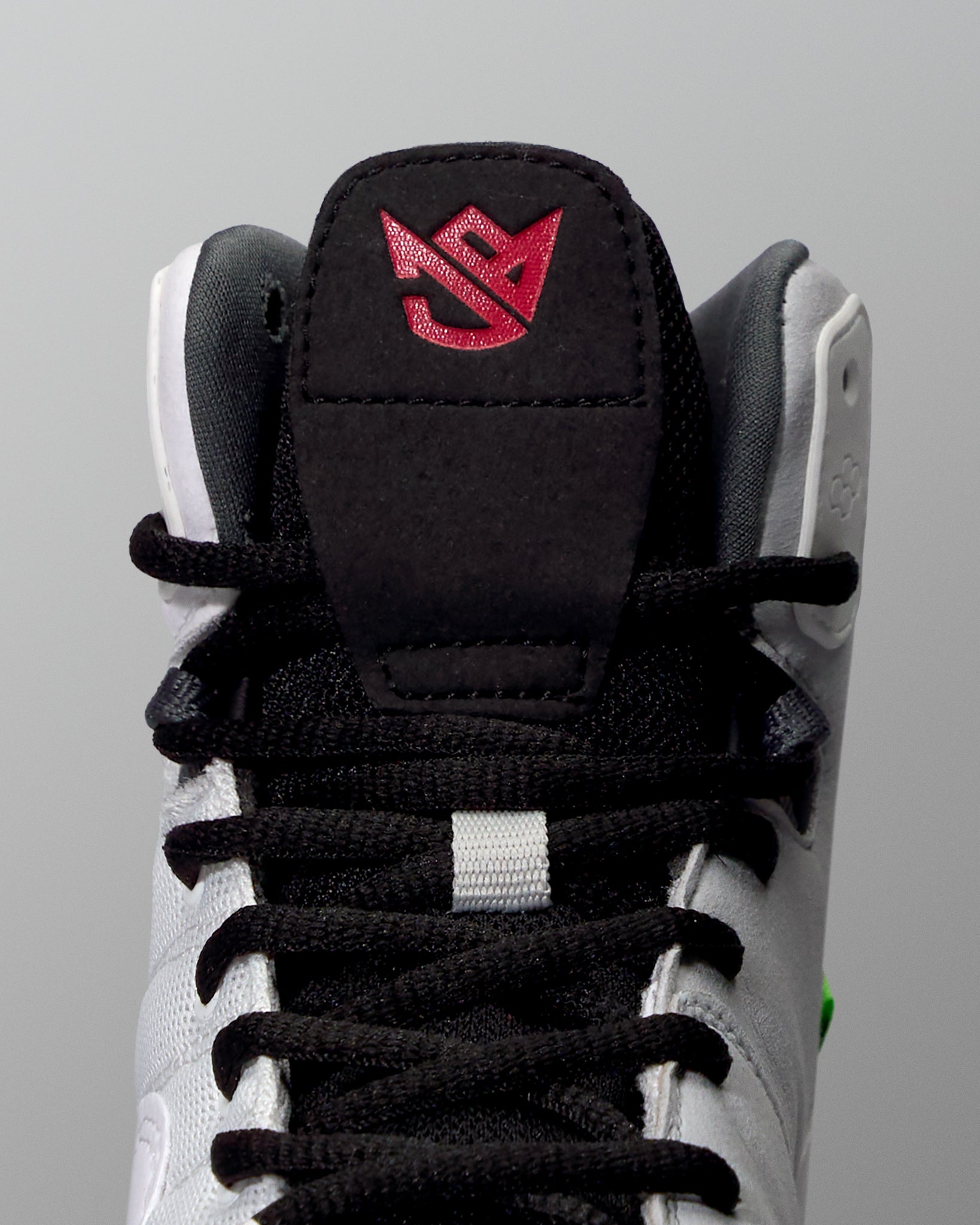 Close-up of a black and white wrestling shoe with a red logo on a gray background