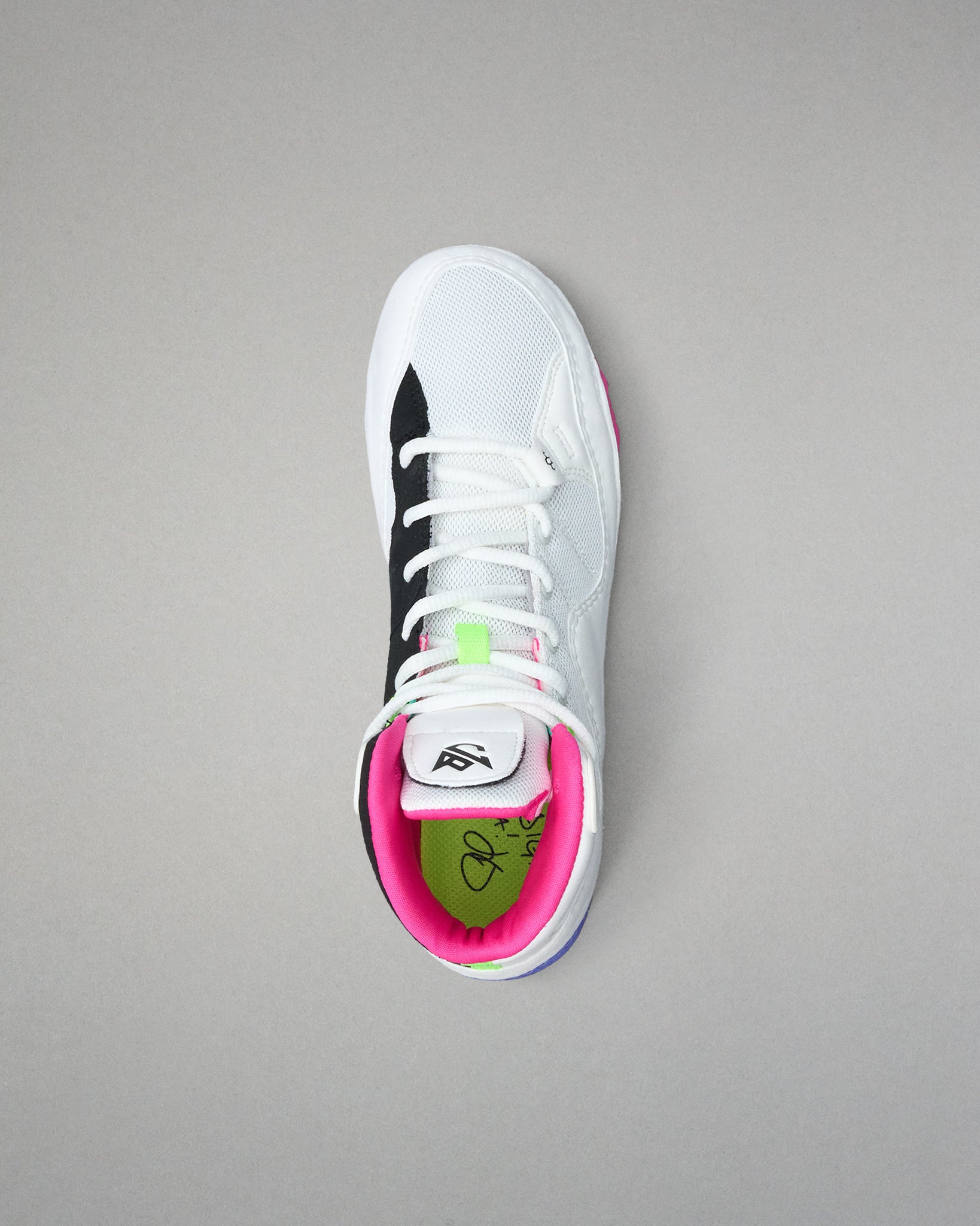White wrestling shoe with black and pink accents on a gray background