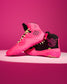 A pair of high-top wrestling shoe in vibrant pink and black, featuring a geometric flower logo on the side and a stylized 'Jordan Burroughs' logo on the heel, set against a solid pink background.