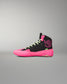 A high-top athletic wrestling shoe in black and neon pink, featuring lime green laces and a small green tag near the heel, shown against a neutral gray background.
