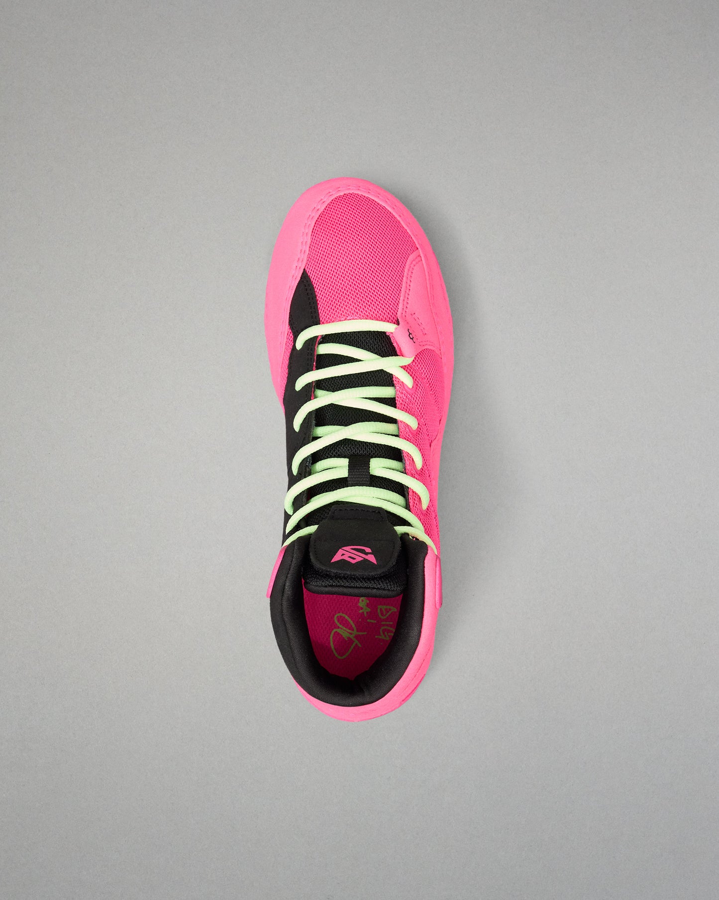 A single high-top wrestling shoe shown from a top-down view on a neutral gray background. The shoe features a vibrant hot pink upper and sole, black overlays, neon yellow-green laces, and a black collar.