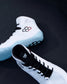 A pair of white high-top wrestling shoes with black laces and accents, featuring a light blue textured outsole and a red-and-black geometric logo on the side, displayed on a dark background.