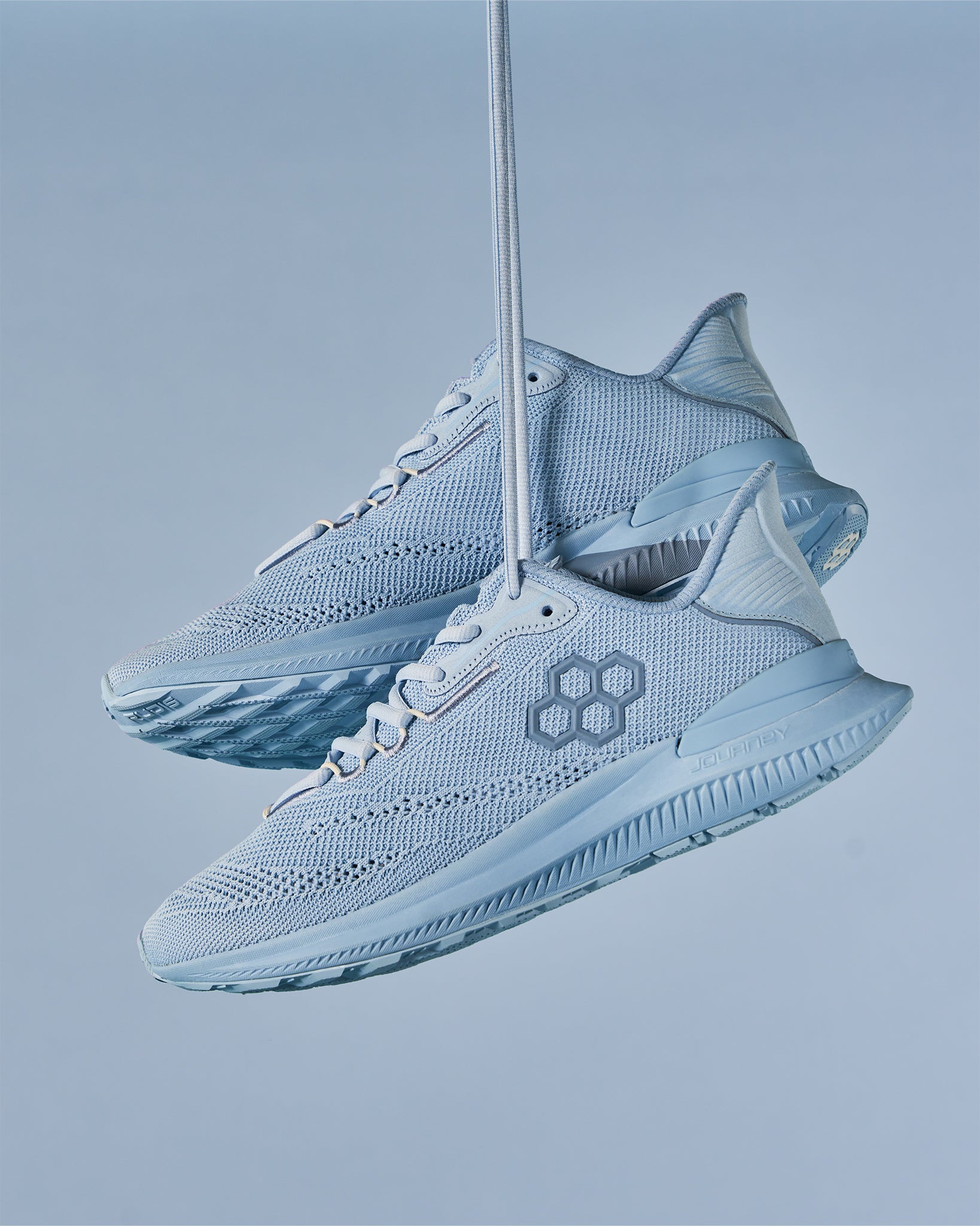 Light blue athletic shoes suspended against a soft blue background featuring a breathable mesh upper and designed for performance