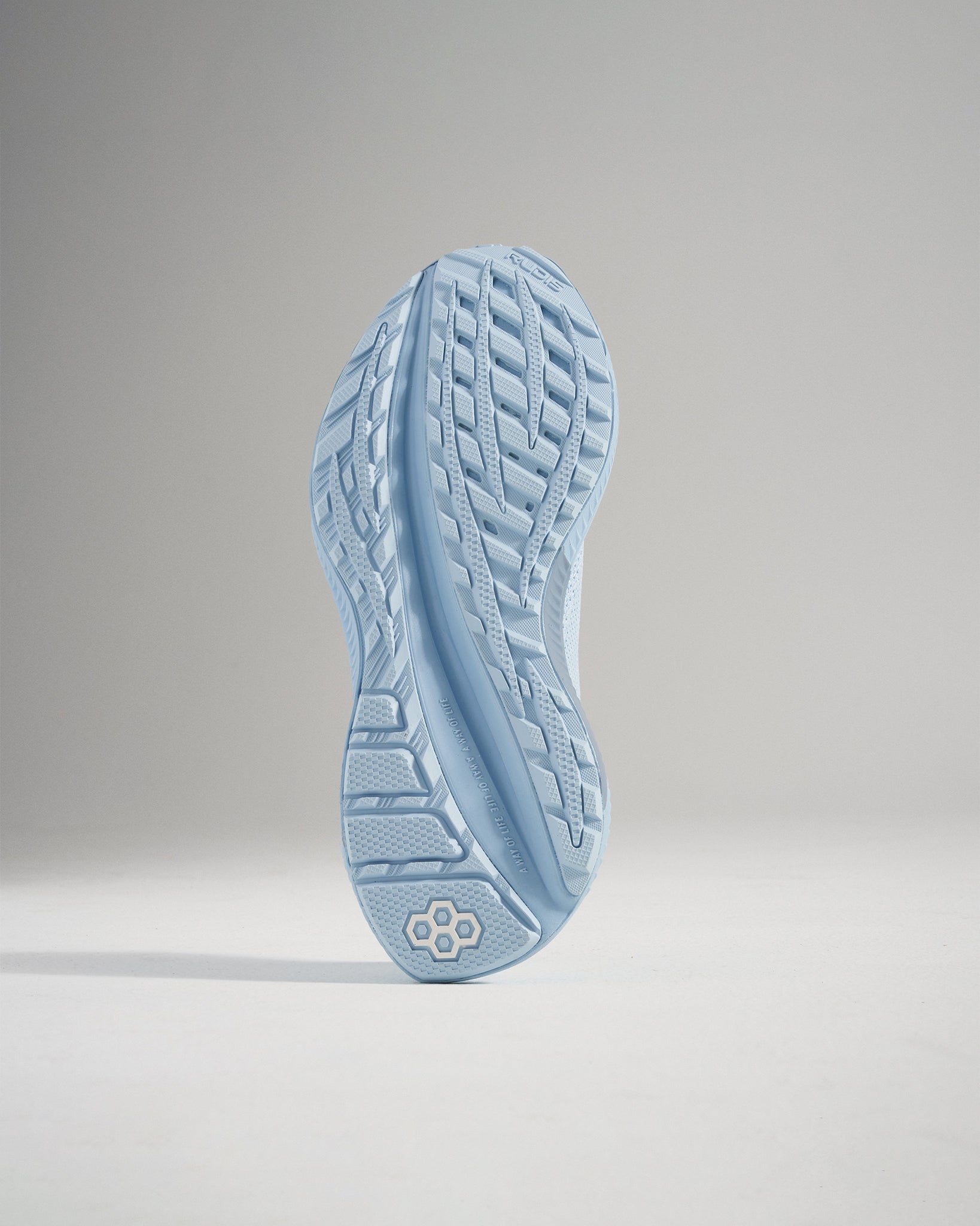 The image features a close-up of a light blue running shoe sole showcasing its unique tread pattern and design elements that enhance grip and stability