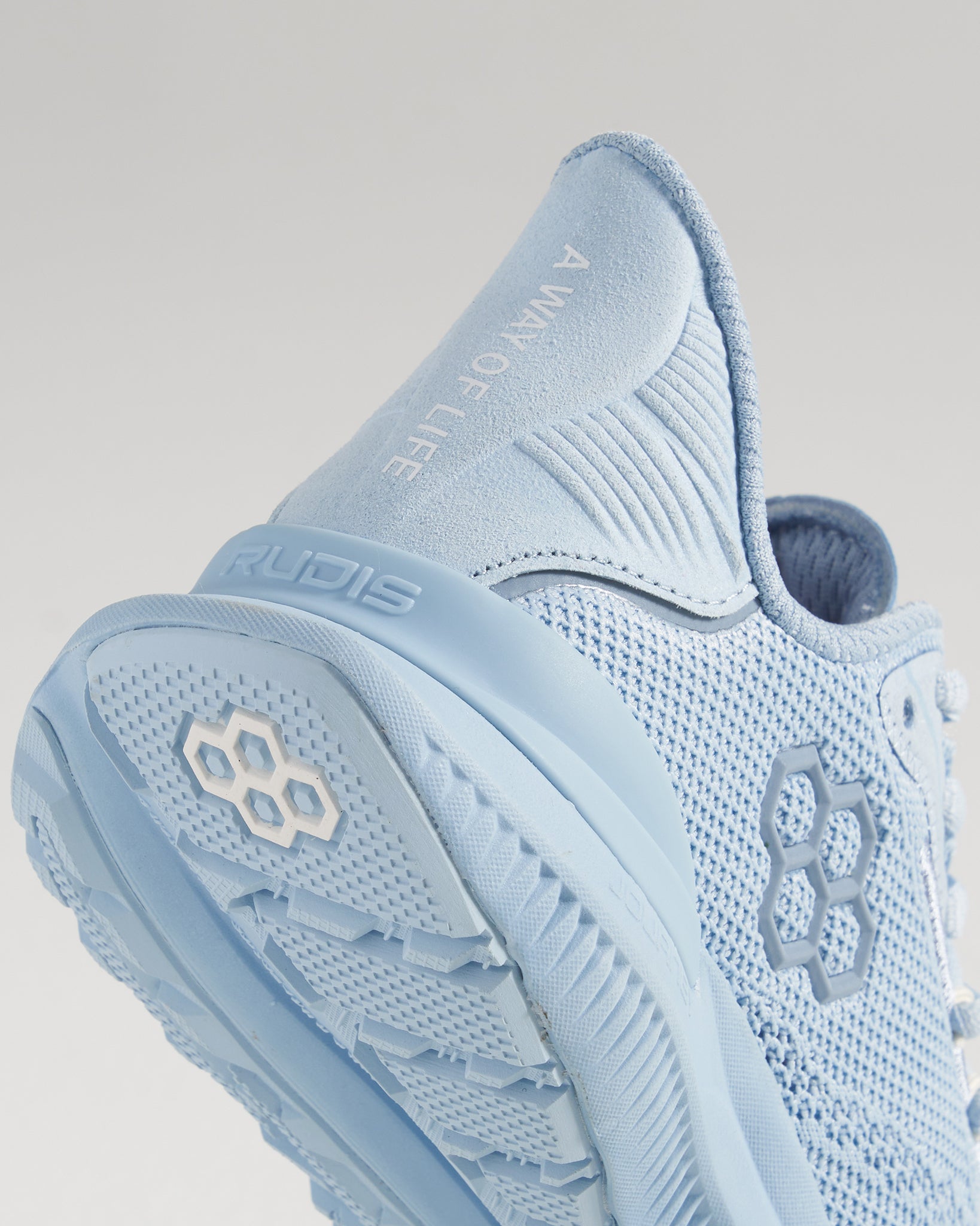 A close-up view of a light blue athletic shoe featuring a textured mesh upper and a detailed sole design emphasizing comfort and performance