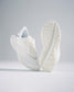 A pair of modern white athletic shoes featuring a breathable mesh upper intricate sole design and a minimalist aesthetic