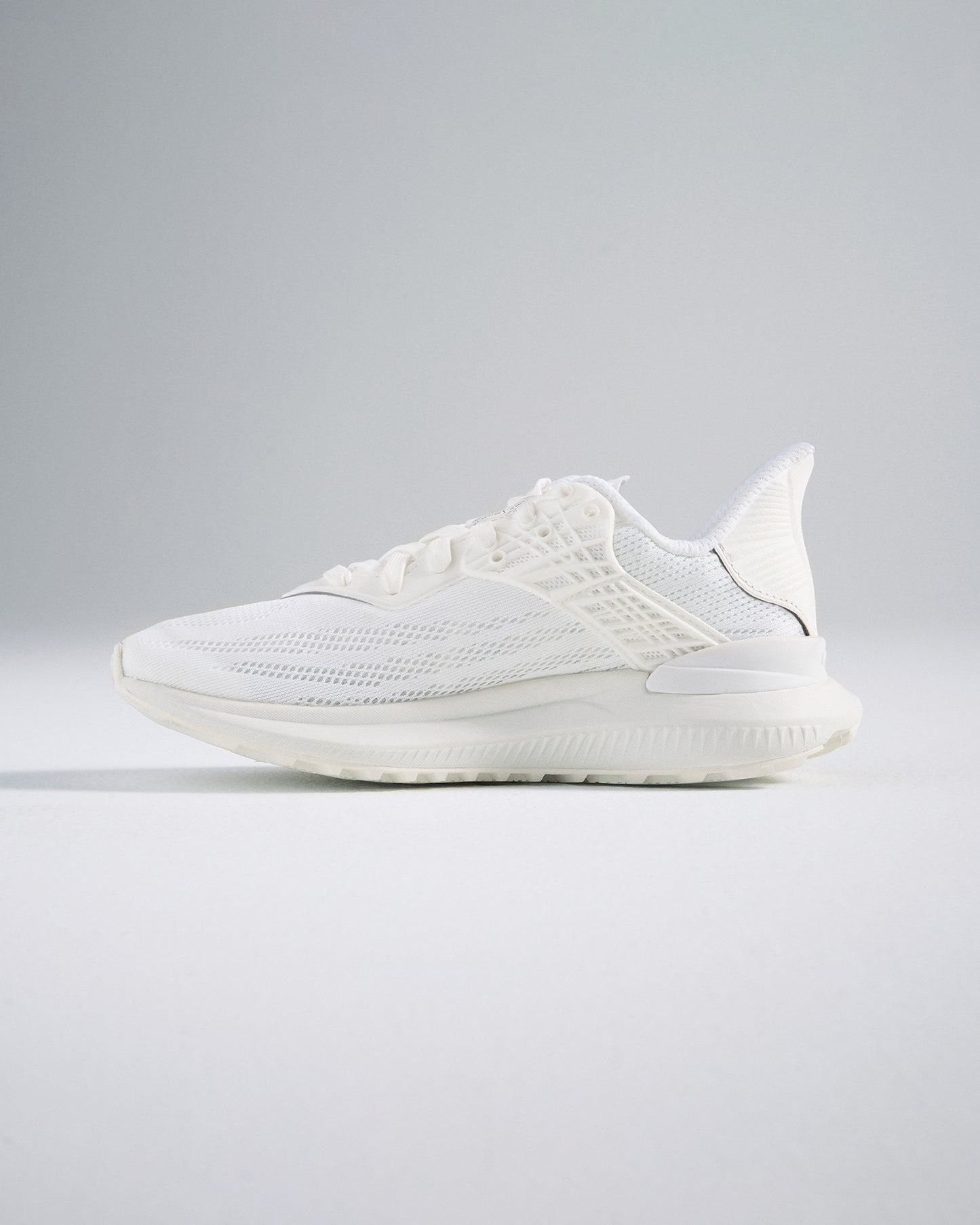 A side view of a sleek white athletic shoe featuring a breathable design and cushioned sole ideal for fitness activities