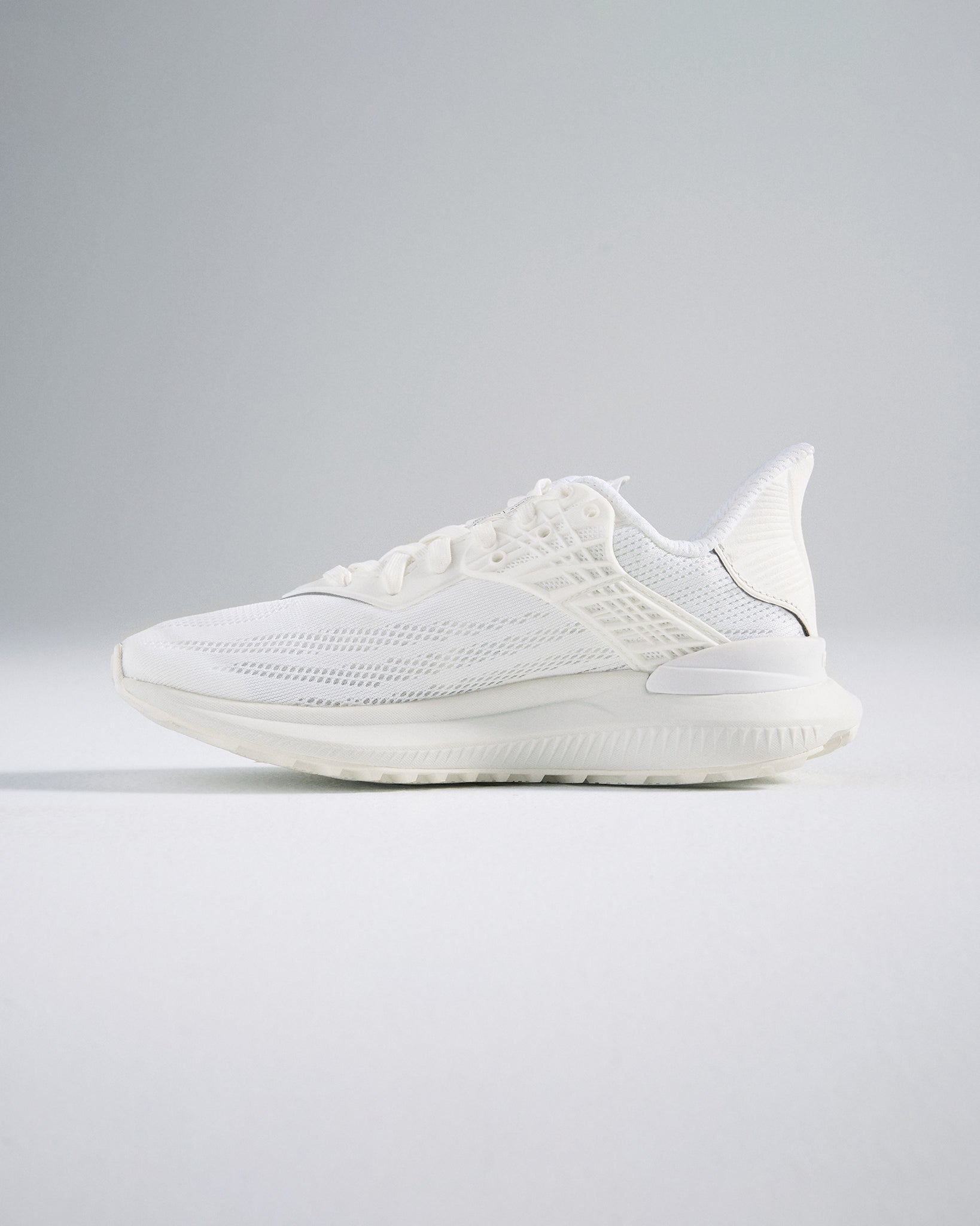 A side view of a sleek white athletic shoe featuring a breathable design and cushioned sole ideal for fitness activities