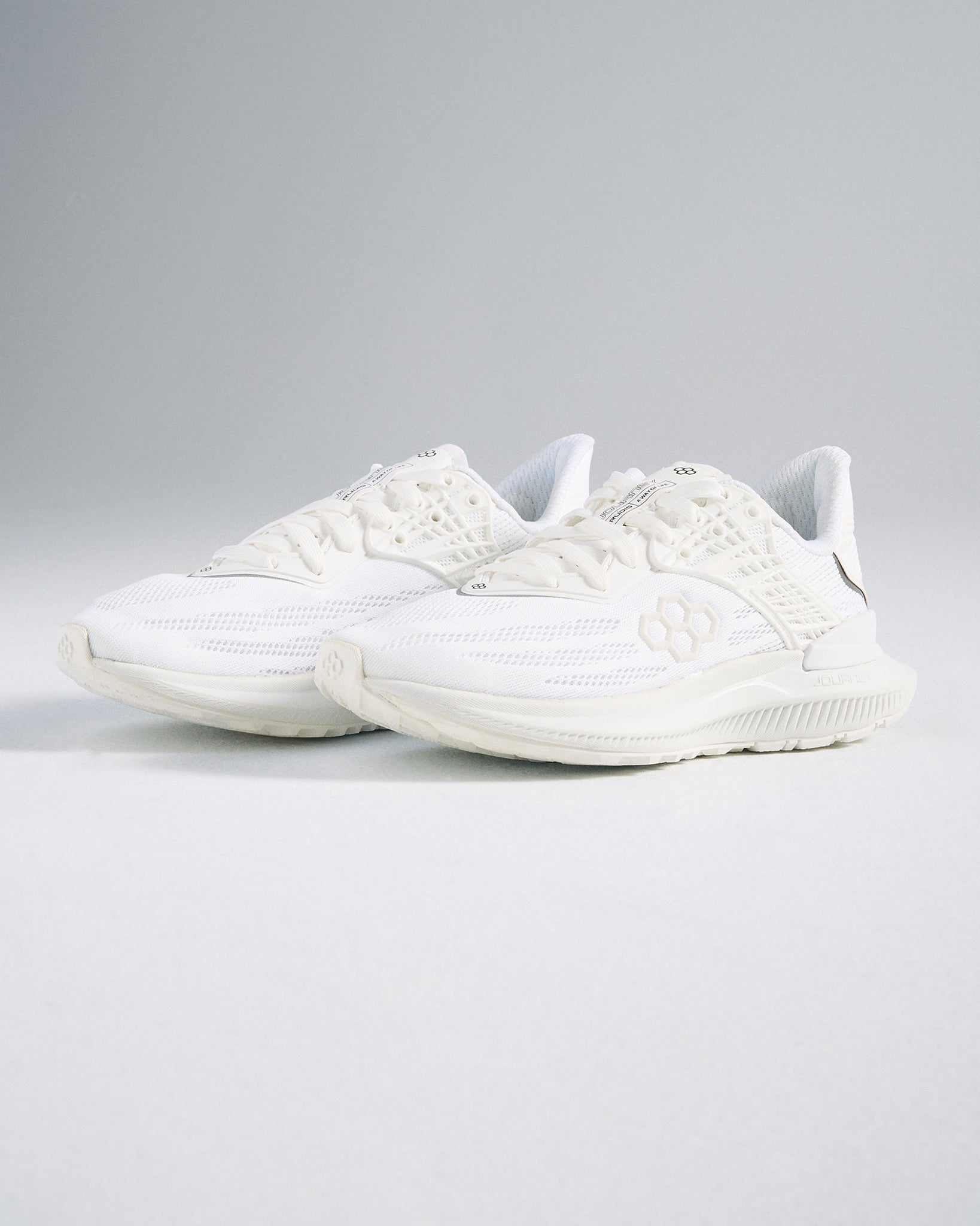 A pair of modern white athletic shoes featuring a sleek design breathable mesh upper and textured sole for performance and comfort