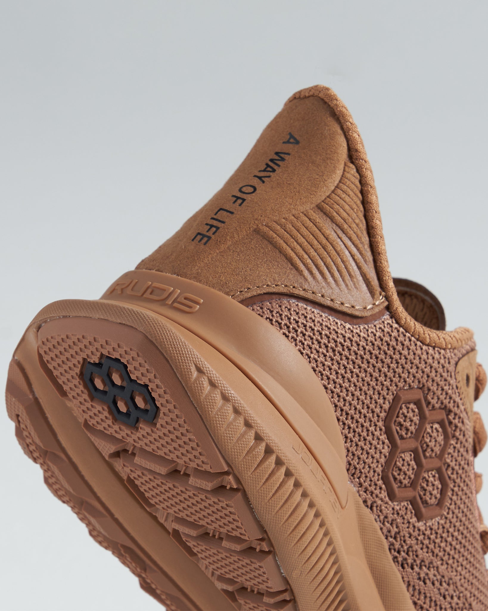 A close-up view of a brown athletic shoe featuring a breathable mesh design textured sole and branding elements that emphasize its functionality and style