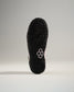 A close-up view of the textured black sole of a sneaker featuring a pink accent and a modern design