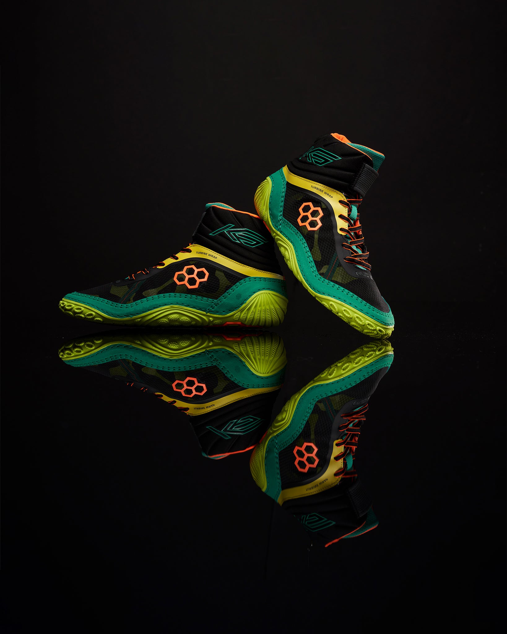A pair of high-performance black basketball shoes with vibrant green and orange accents featuring a textured sole and unique design elements