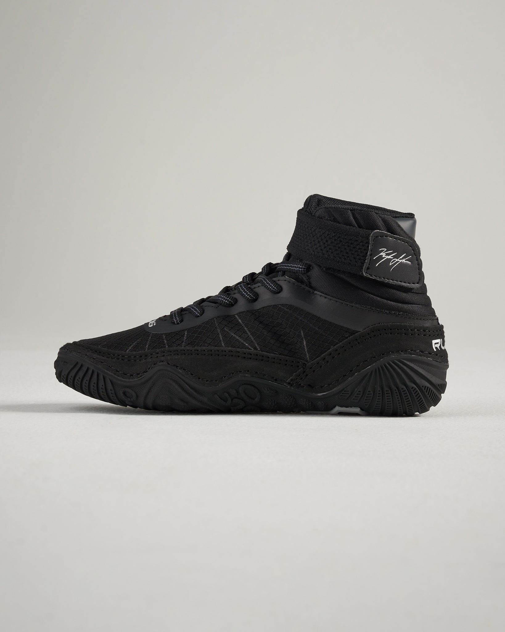This image features a modern black athletic shoe with a high-top design showcasing a sleek silhouette textured upper and a flexible sole suitable for performance and style