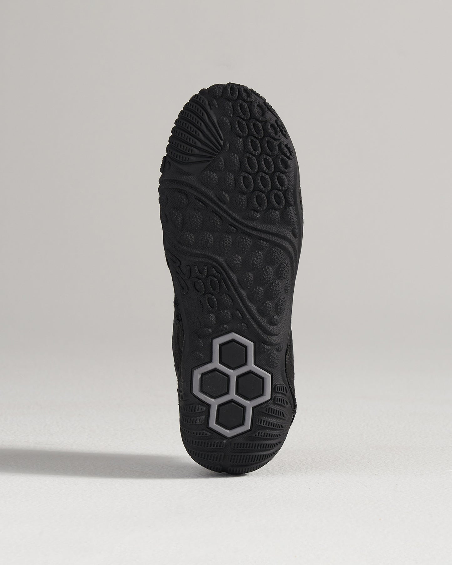 A close-up view of a black athletic shoes sole showcasing detailed tread patterns and a unique hexagonal design feature