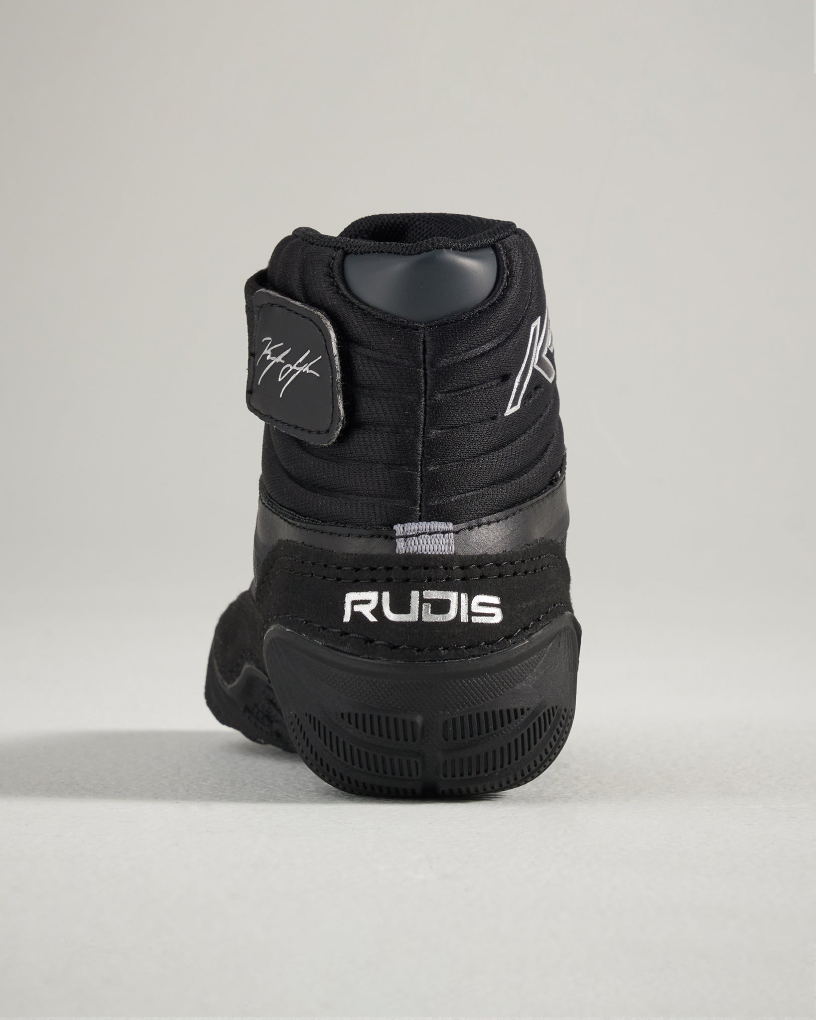 A close-up view of a black athletic shoe featuring a signature and branding showcasing its design and structure from the rear perspective