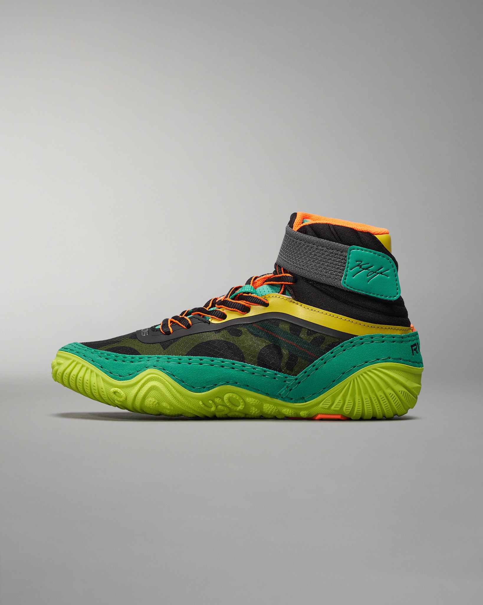 A vibrant high-top athletic shoe combines black green and orange elements for a striking look