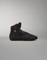 High top black athletic shoe showcasing red accents and textured design, featuring a padded ankle collar for stability against a soft gray background.