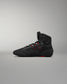 High-top athletic shoe shown in black with red accents and a textured surface for grip, set against a neutral gray background.