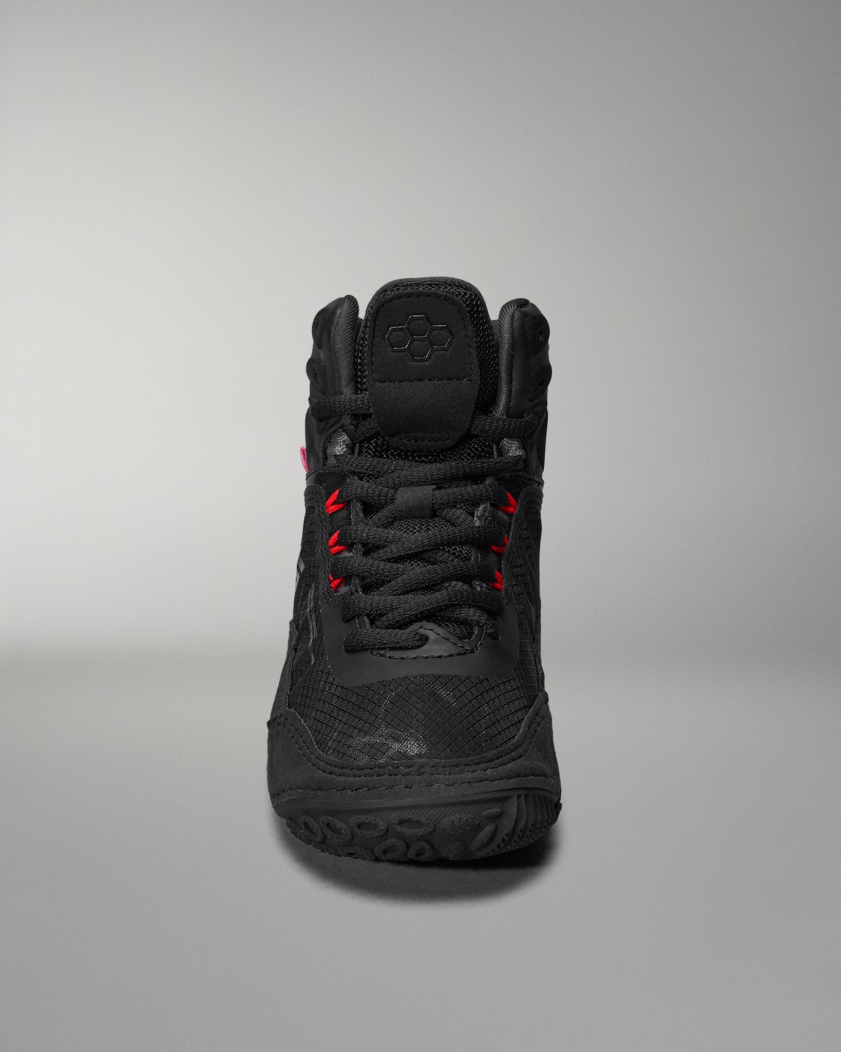 Black high-top athletic shoe features textured detailing and red accents, designed for comfort and performance, presented against a soft gray background.