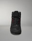 Black high-top athletic shoe features textured detailing and red accents, designed for comfort and performance, presented against a soft gray background.