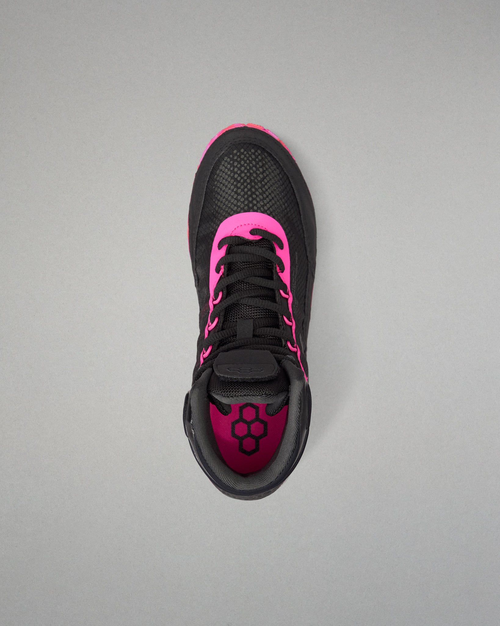 A black athletic wrestling shoe with vibrant hot pink accents, shown from a top-down view on a neutral gray background.
