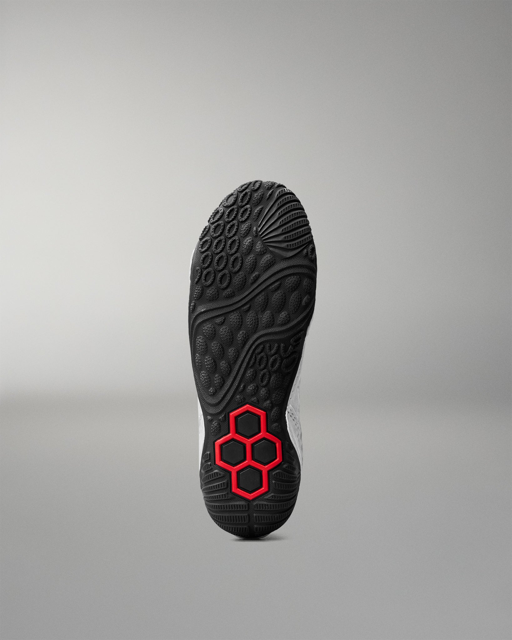 Bottom outsole view of RUDIS Infinity Edge wrestling shoe featuring aggressive traction pattern and red hex grip technology